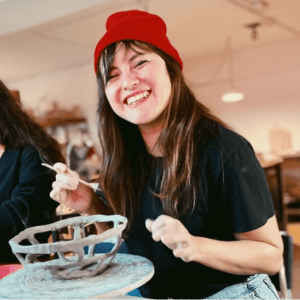 Mujer sonriente haciendo pieza de ceramica
