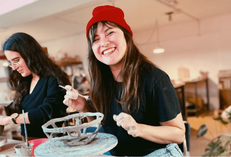 Mujer sonriente haciendo pieza de ceramica